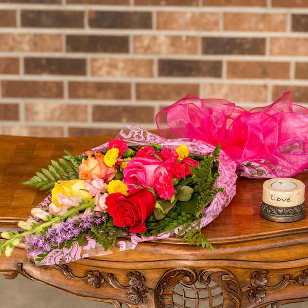Bouquet of mixed roses and small flowers wrapped in pink paper