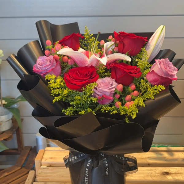 Bouquet of red and pink roses with lilies wrapped in black paper