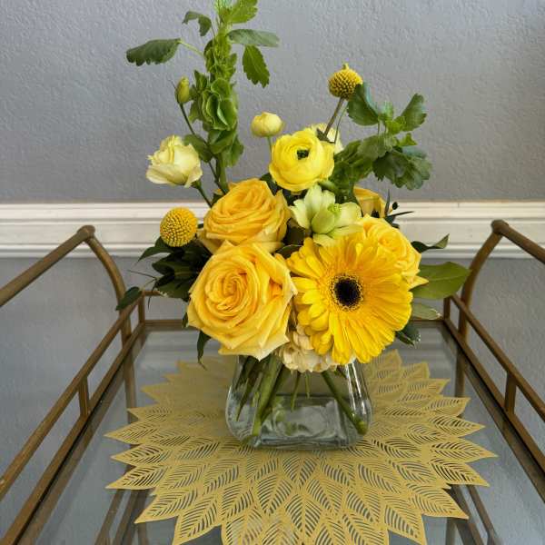 Yellow roses and a gerbera daisy in a glass vase