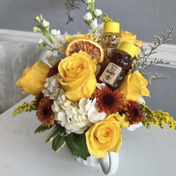 Yellow roses and white flowers arranged in a white mug with honey jars