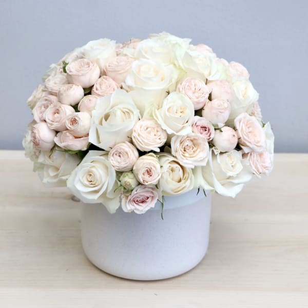 White and blush roses arranged in a white vase