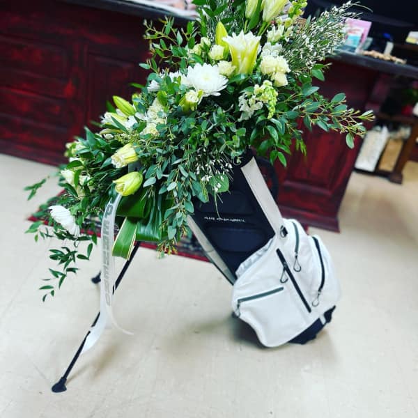 Large white floral spray on a stand with a white backpack attached