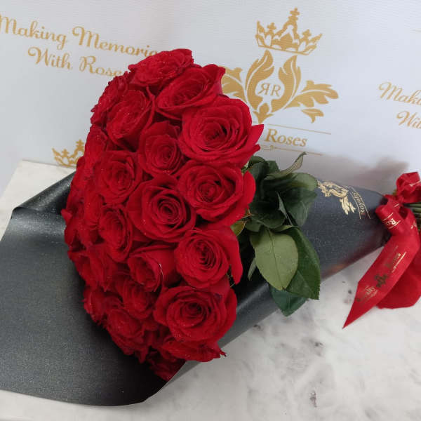 Bouquet of red roses wrapped in black paper with a red ribbon