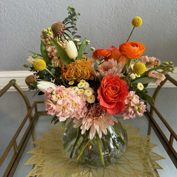 Mixed bouquet in a clear glass vase with orange and blush flowers