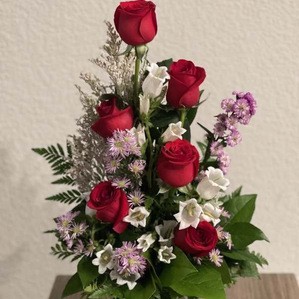 Red roses and white bellflowers in a clear glass vase