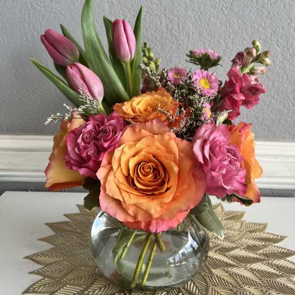 Pink tulips and orange roses arranged in a glass vase