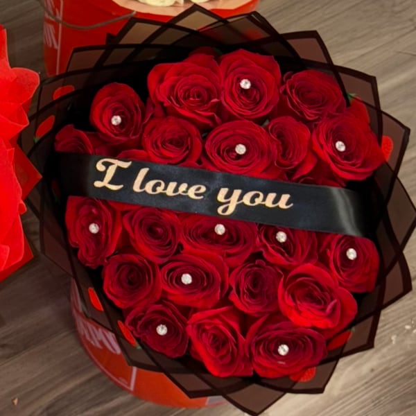 Red roses wrapped in black paper with a "I love you" ribbon