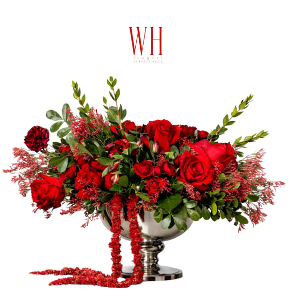 Red rose arrangement in a silver pedestal bowl with trailing red accents
