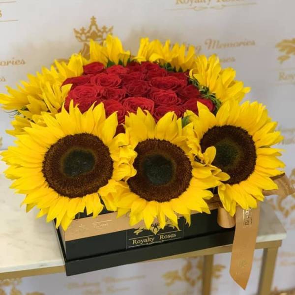Boxed bouquet of red roses surrounded by bright yellow sunflowers