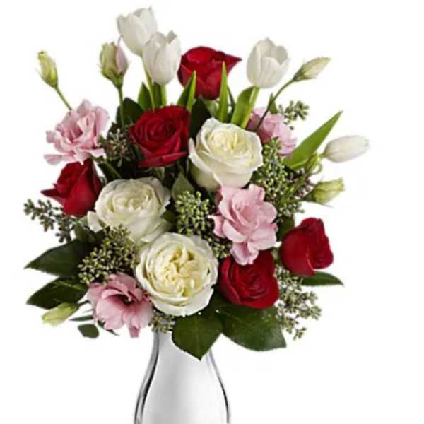 Bouquet of red and white roses with pink blooms in a clear glass vase
