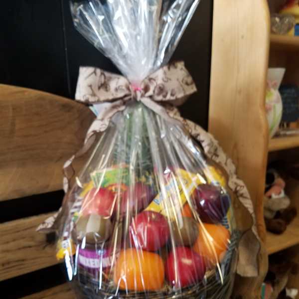 Cellophane-wrapped fruit and snack gift basket tied with a patterned bow.