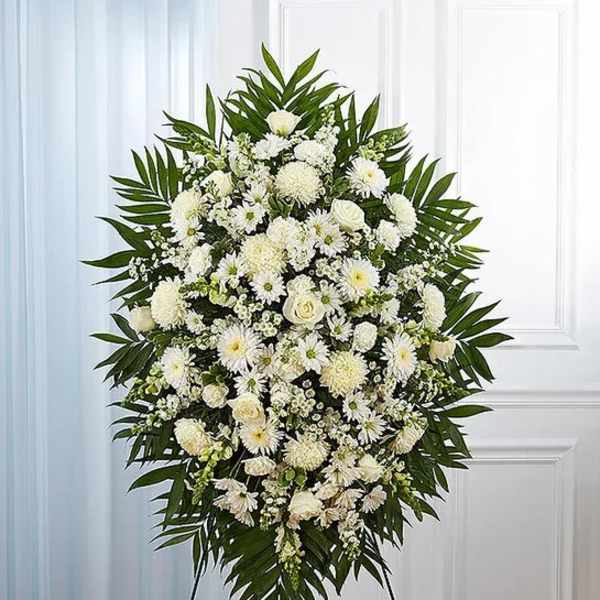 White funeral spray with daisies and roses on a stand
