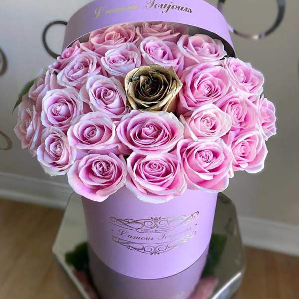 Round hatbox of light pink roses with a single gold rose in a lavender cylinder box