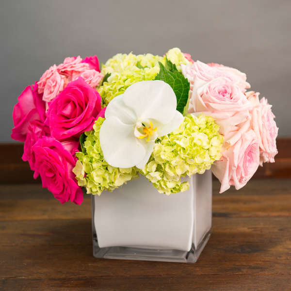 Pink and pale rose bouquet with white orchid in a square vase