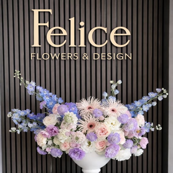 Pastel floral arrangement in a white urn with blue and lavender blooms