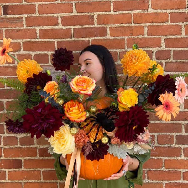 Woman holding a pumpkin filled with colorful flowers