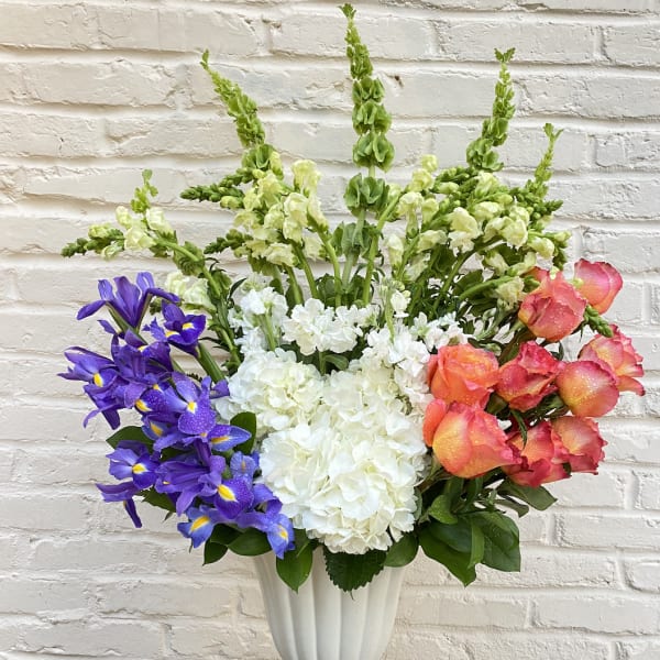 Colorful mixed flower arrangement in a white pedestal vase