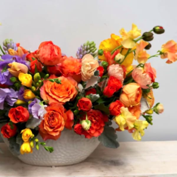 Colorful bouquet of mixed flowers in a white bowl vase