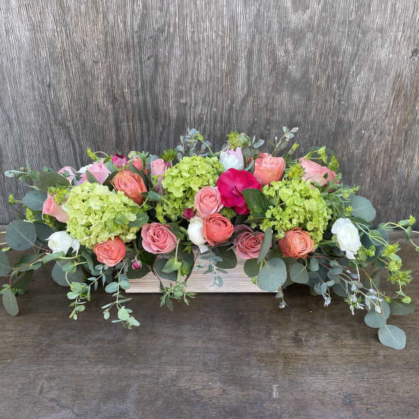 Low floral centerpiece with pink and coral roses and green hydrangeas