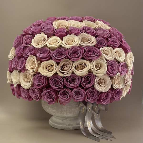 Round arrangement of pink and cream roses in a gray vase