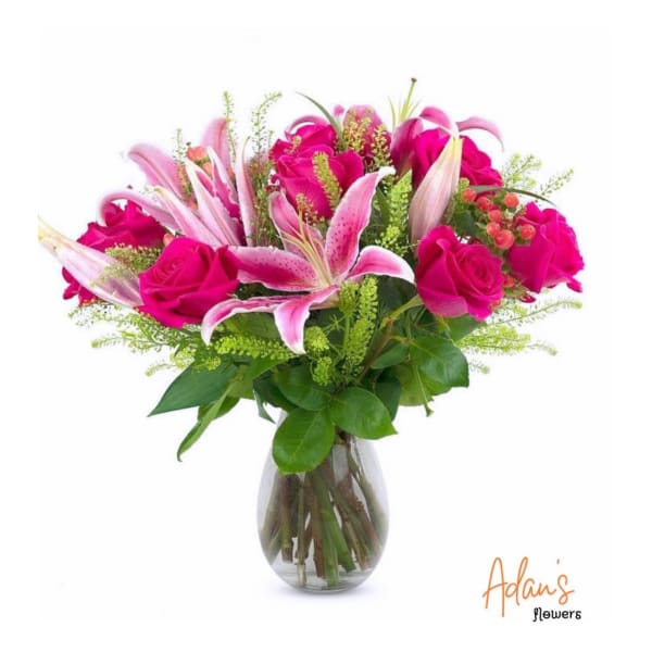 Pink roses and lilies arranged in a clear glass vase