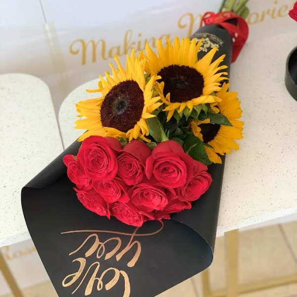 Bouquet of red roses and yellow sunflowers wrapped in black paper