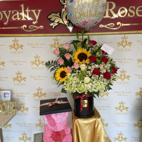 Birthday balloon above a mixed flower arrangement with roses and sunflowers