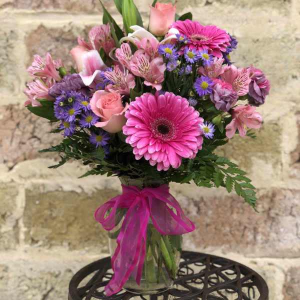 Pink and purple mixed bouquet in a glass vase with a ribbon