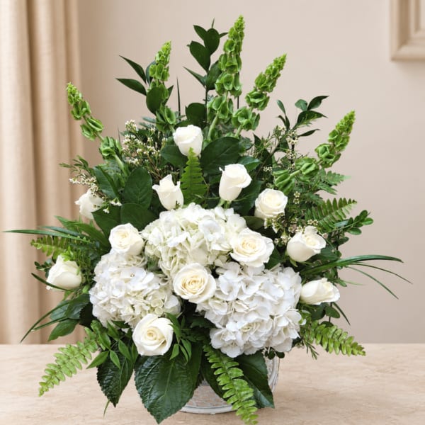 White roses and hydrangeas in a low vase with green foliage