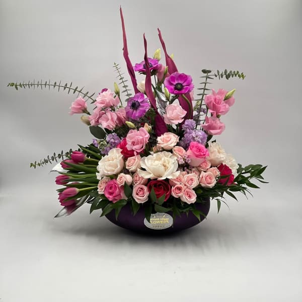 Pink and white floral arrangement in a dark bowl vase