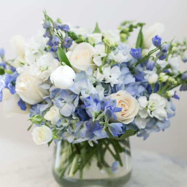 Blue and white bouquet of roses and hydrangeas in a glass vase