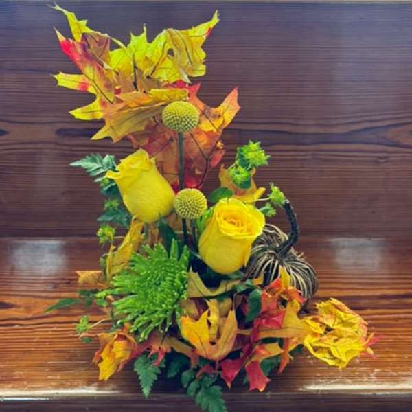 Yellow roses and green pom flowers with autumn leaves and a pumpkin accent