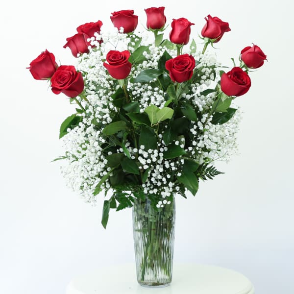 Red roses and baby's breath in a tall glass vase