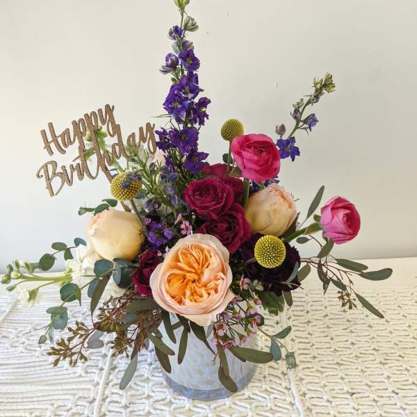 Mixed bouquet in a clear vase with a Happy Birthday sign