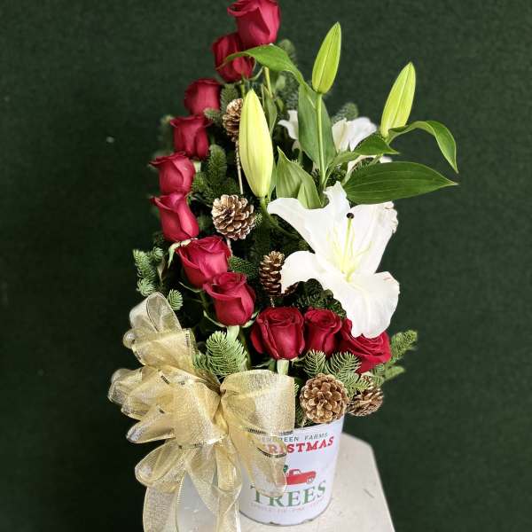 Red roses and white lilies in a festive holiday container with a gold bow