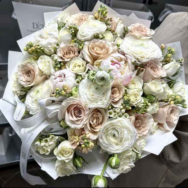 Bouquet of white and blush roses with ranunculus wrapped in white paper