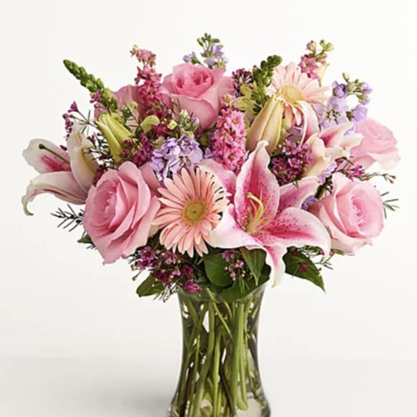 Pink roses and lilies arranged in a clear glass vase