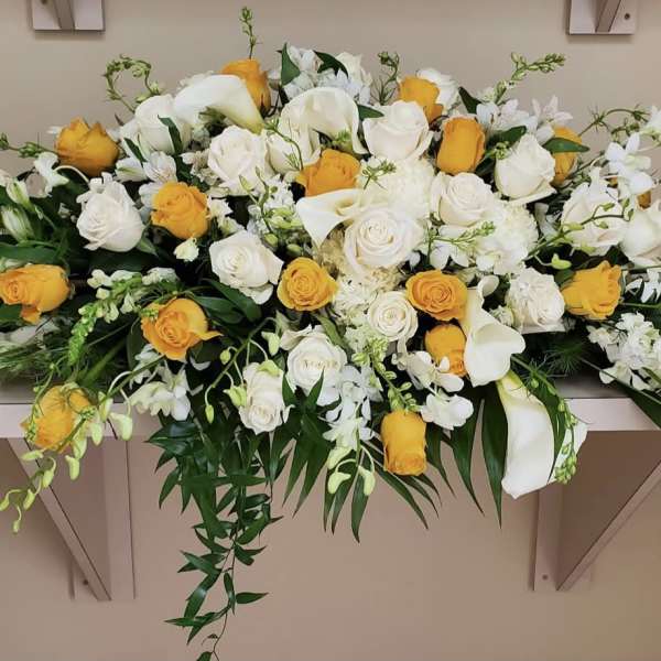 Long floral arrangement of white and yellow roses with white lilies