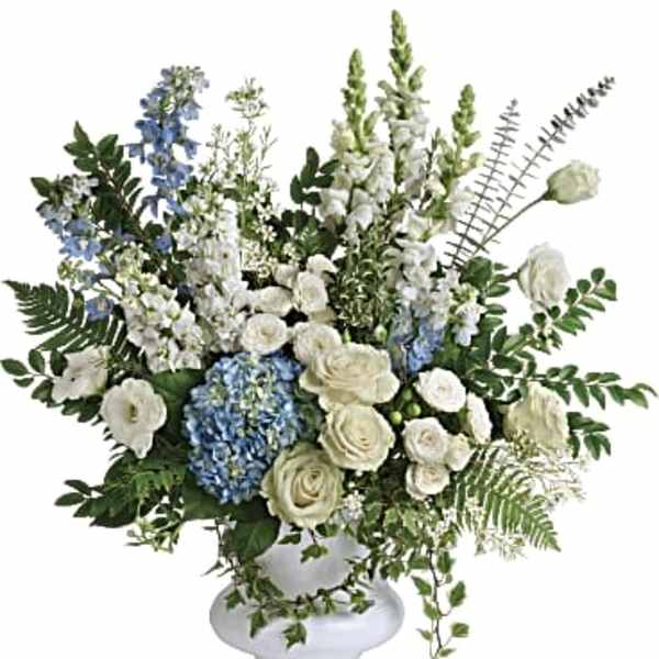 White and blue floral arrangement in a white pedestal vase