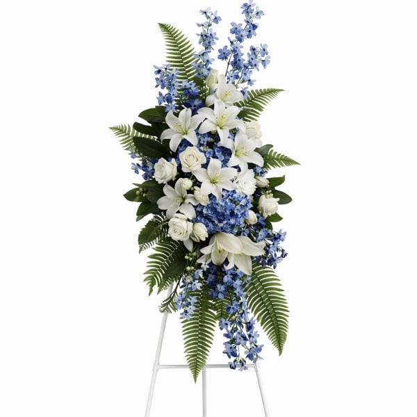 Standing floral spray with white lilies and blue flowers on an easel