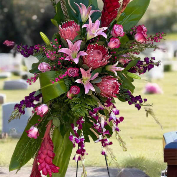 Tall tropical floral spray with pink lilies and red protea on a stand