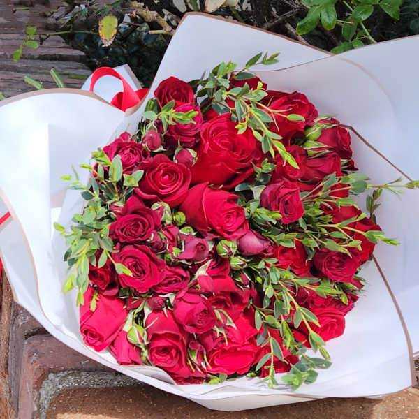 Bouquet of red roses wrapped in white paper with a red ribbon