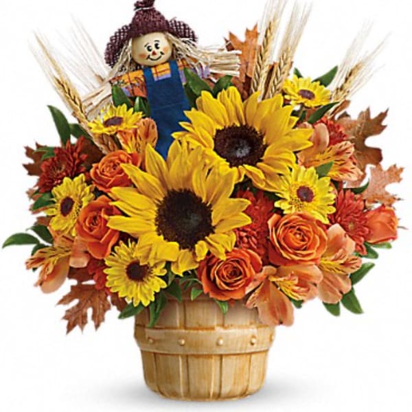Sunflower and rose arrangement in a basket with a scarecrow topper