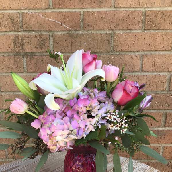 Pink and white floral arrangement in a magenta vase