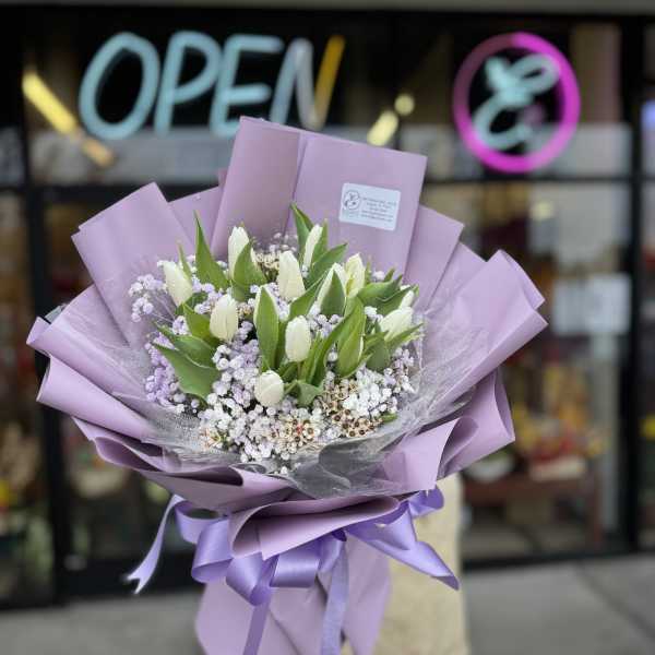 Lavender-wrapped bouquet of white tulips and small purple flowers
