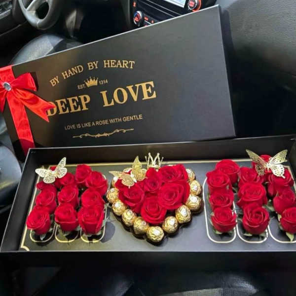 Black gift box with red roses and chocolates arranged inside