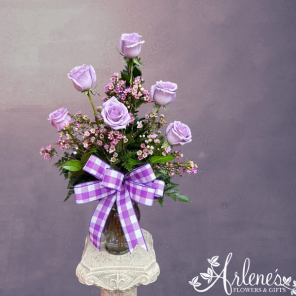 Lavender roses in a glass vase with a purple checkered bow