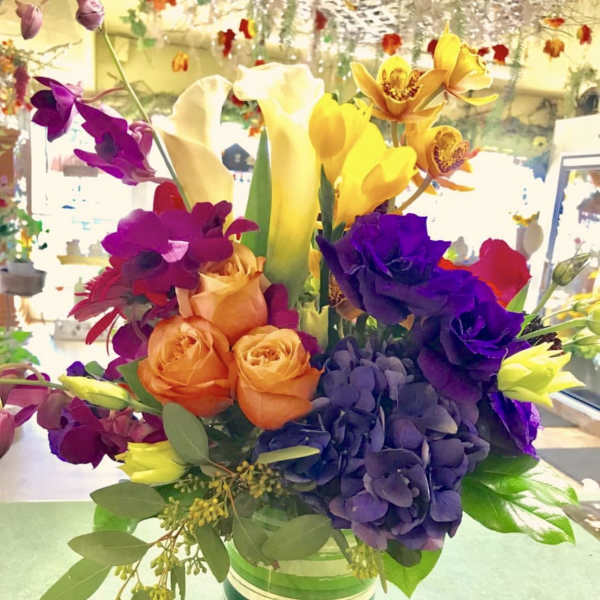 Colorful bouquet with roses, calla lilies, orchids, and hydrangea in a glass vase