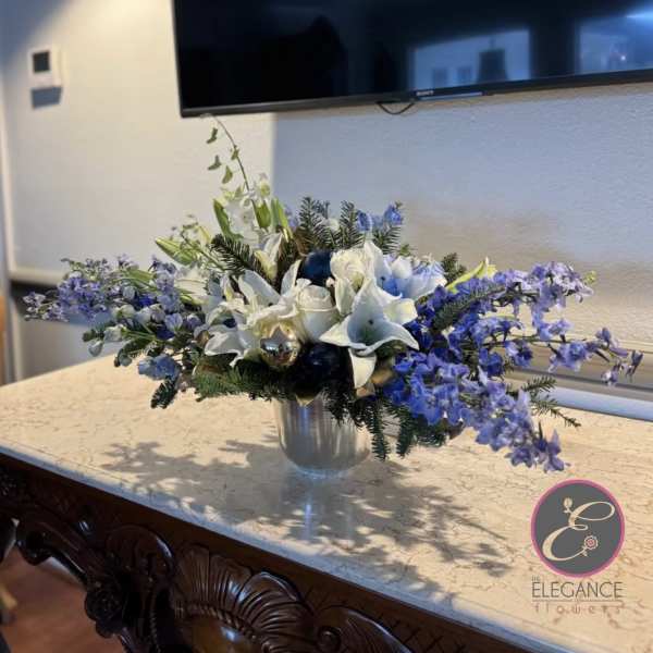 White lilies and blue flowers arranged in a silver vase