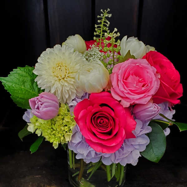 Mixed bouquet of pink, white, and lavender flowers in a glass vase